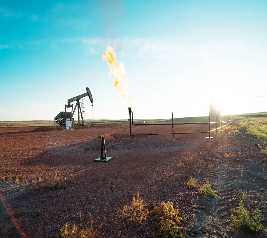 A gas well with an oil pump in the background.