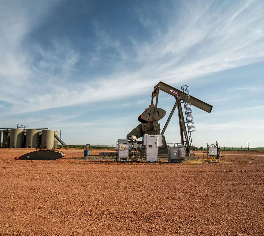 A pump jack is shown in the middle of an open field.