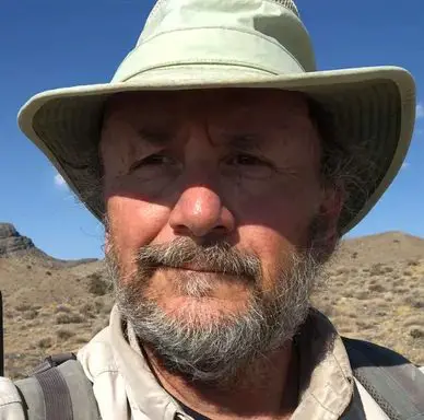 A man with a beard and hat in the desert.