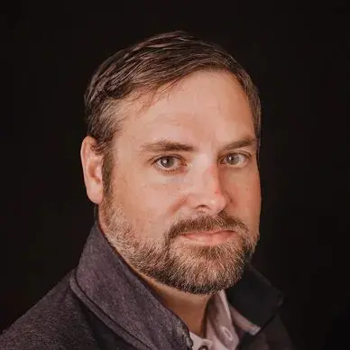 A man with a beard and mustache wearing a jacket.